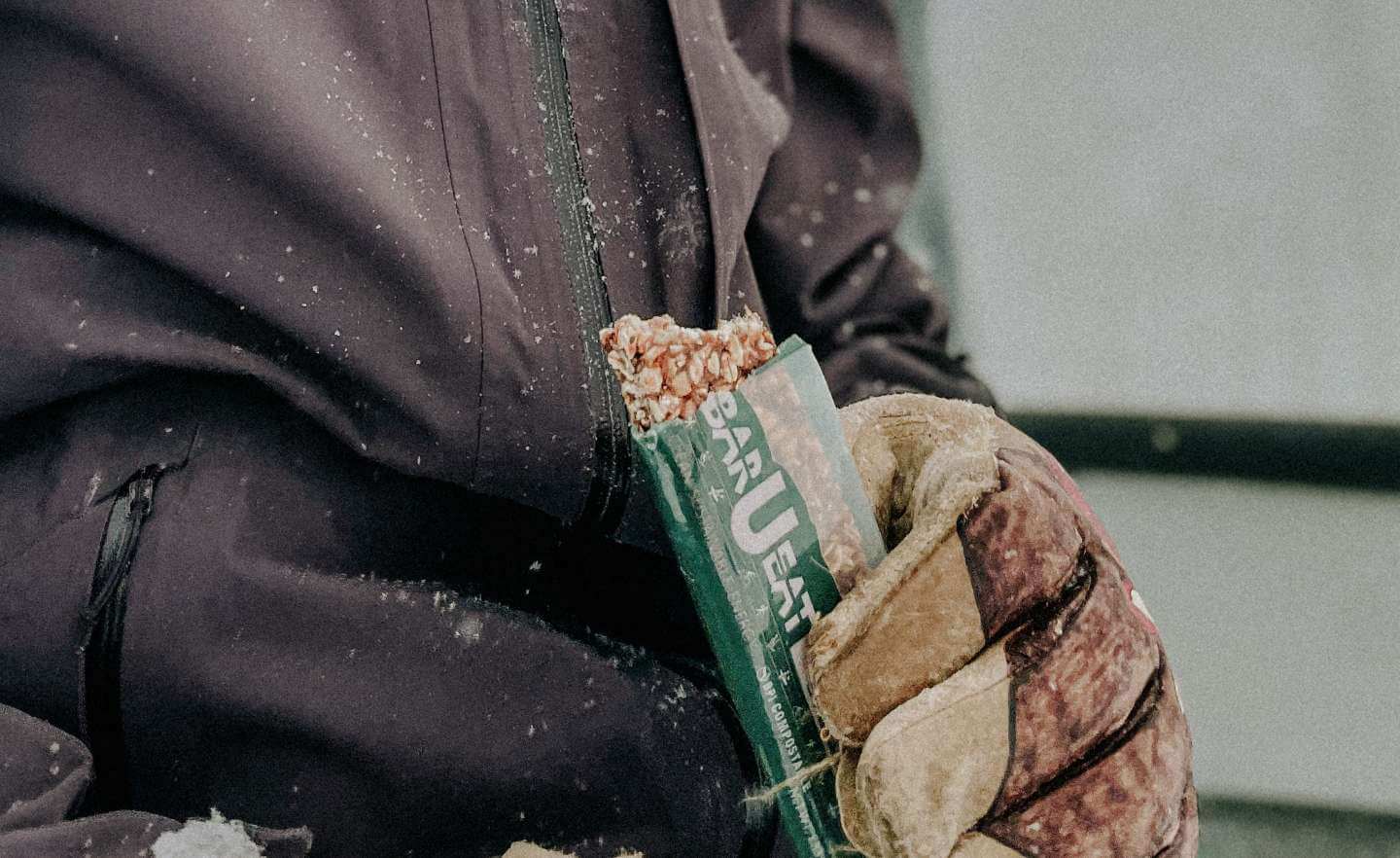 Photograph of a person holding a Bar U Eat bar in the snow