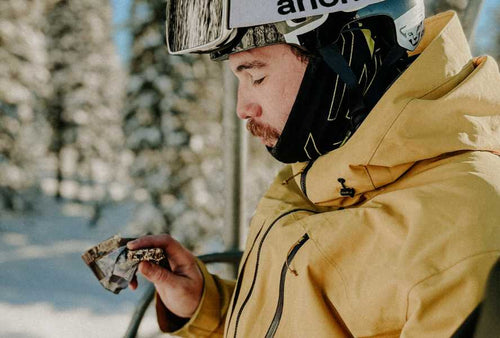 person in ski outfit eating a bar on a ski lift