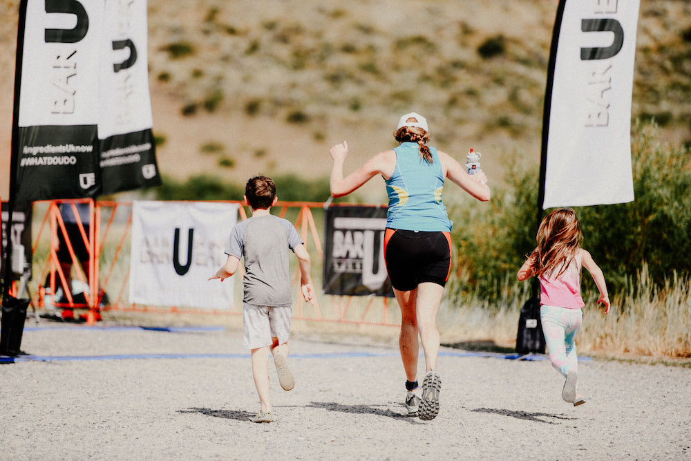 Woman running across a finish line with her kids