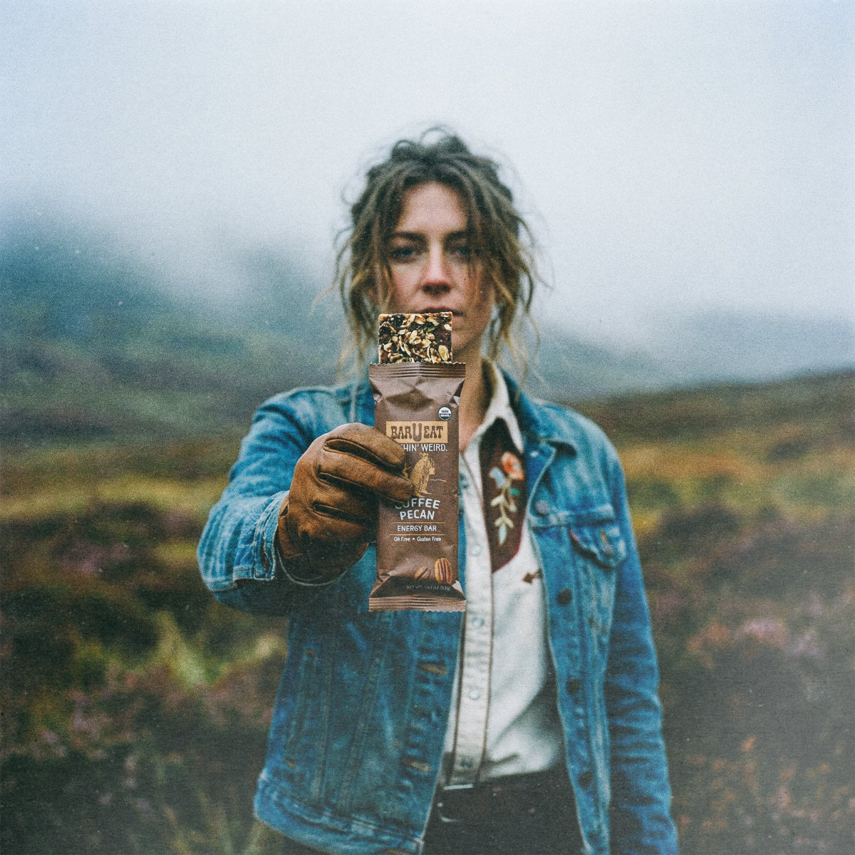 Person holding a package in a natural setting barueat coffee pecan energy bar