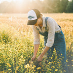 woman in a field harvesting plants wearing a granola farmer hat from barueat
