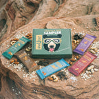 barueat Granola bar sampler set on a rocky surface with various granola bars and nuts.