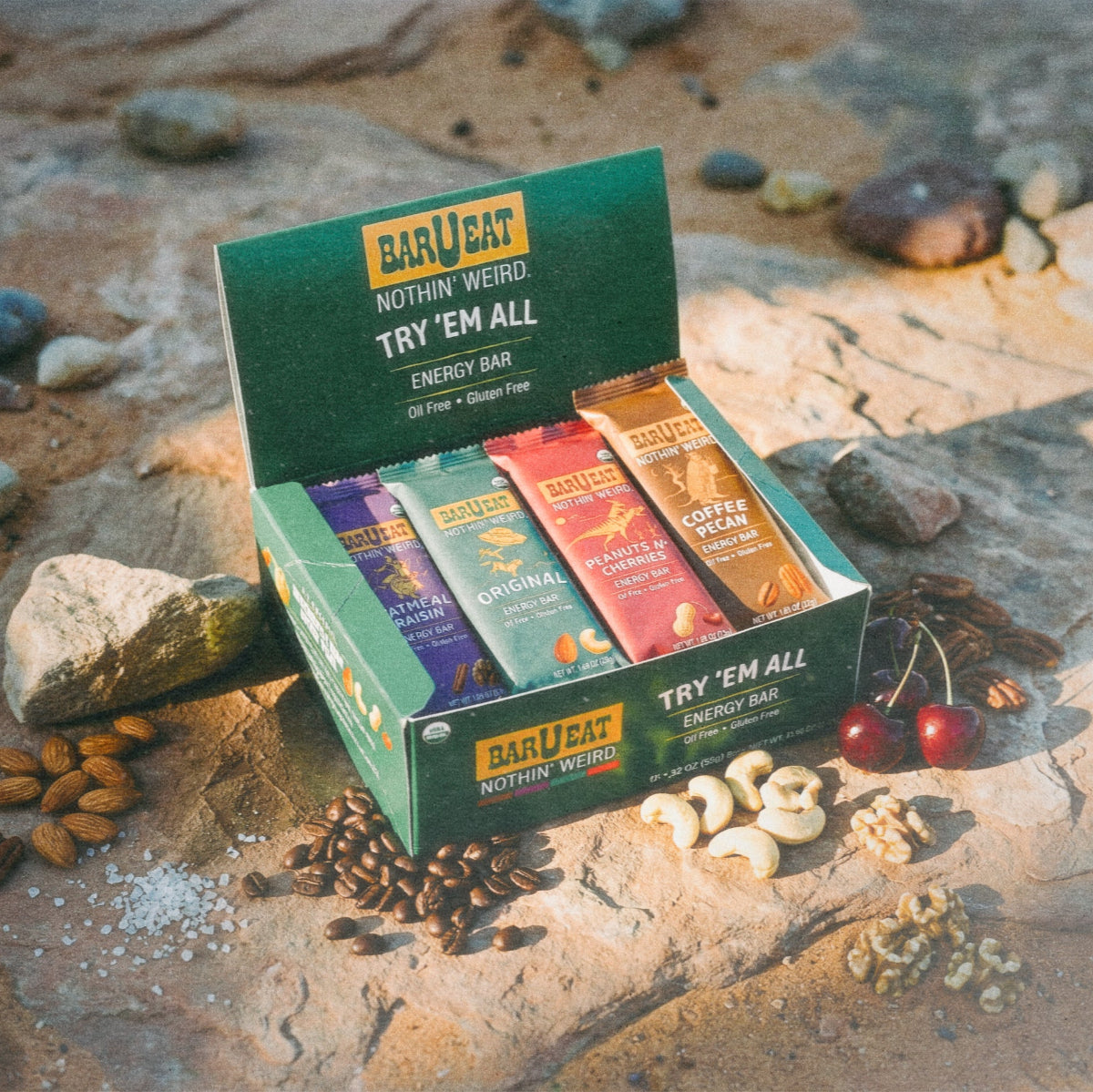 Box of Barbeat energy bar try them all variety box on a rocky surface with various bars visible