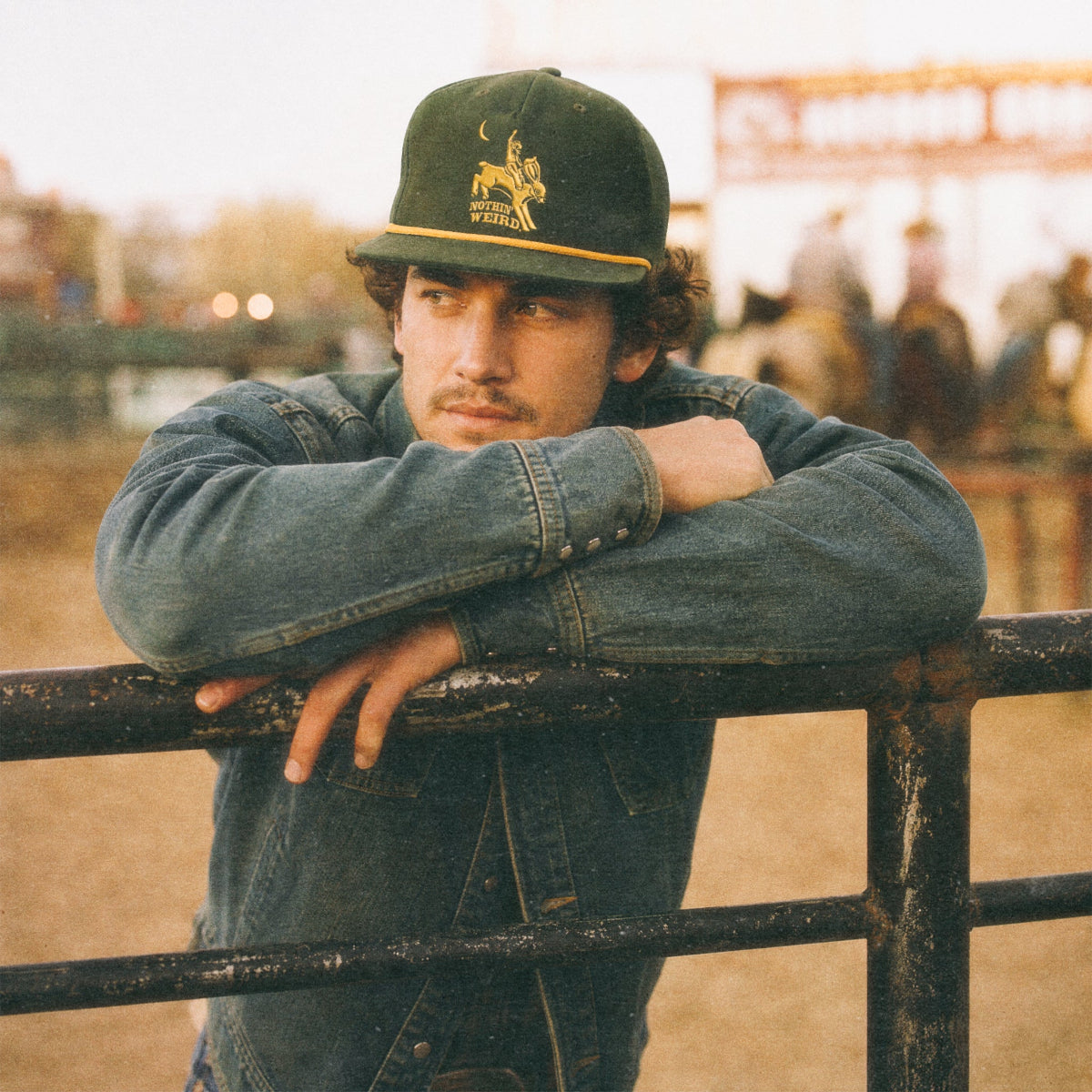 man leaning on the fence at a rodeo