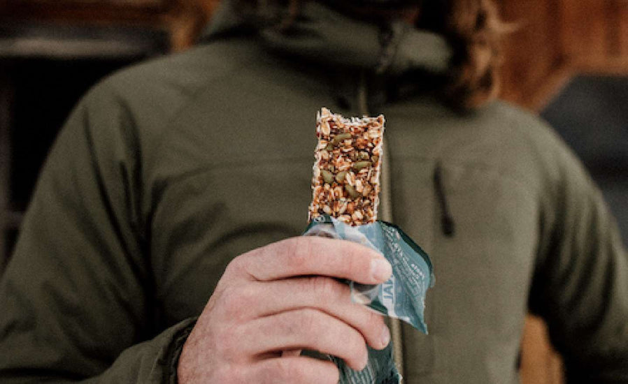 Photograph of a person holding a granola bar close up.