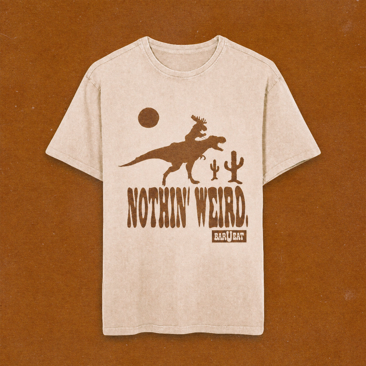 beige t-shirt with moose riding a t-rex with Nothin' Weird text underneath