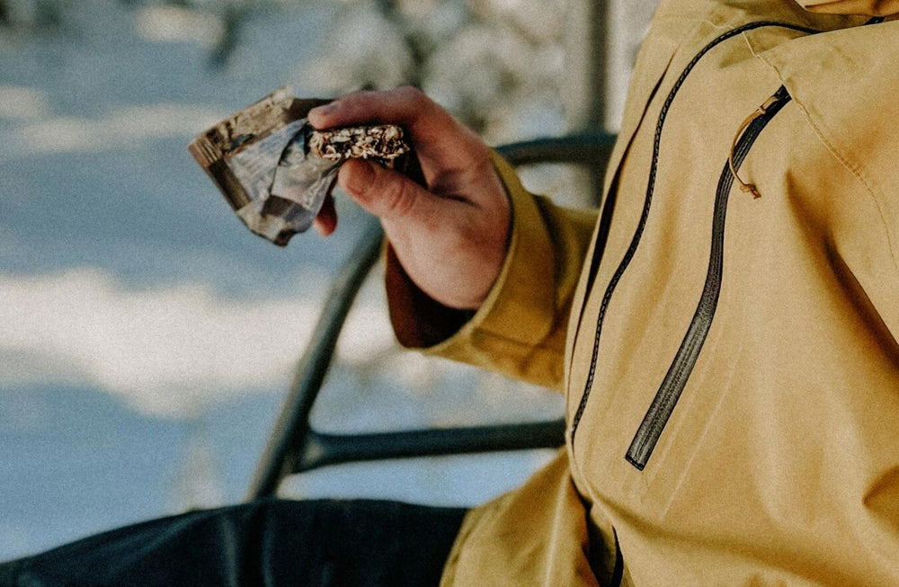 person eating a bar on a chairlift