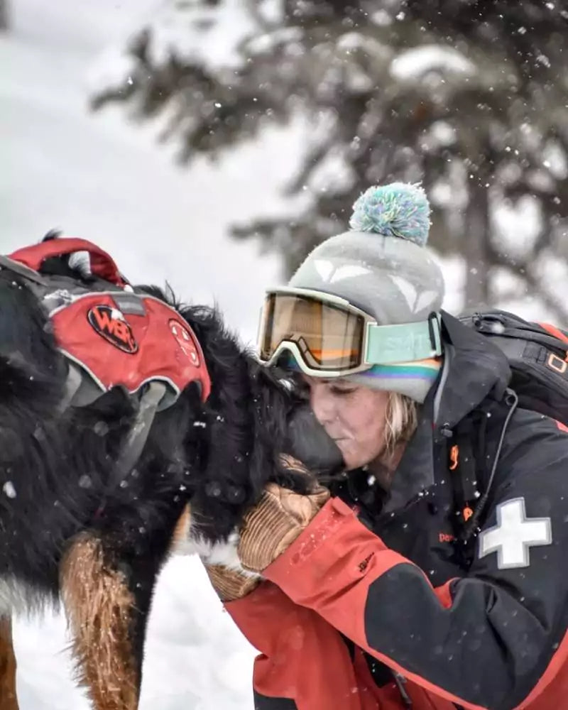 Photograph of Shannon Finch, holding a rescue dog out on the ski slopes