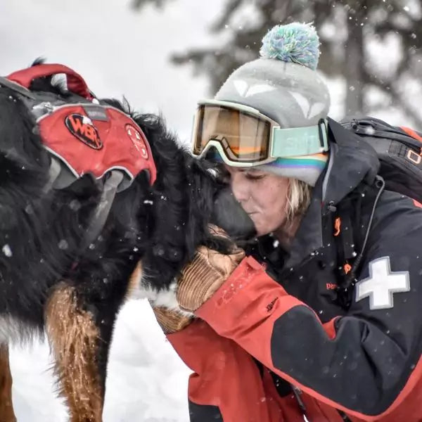 Shannon holding her search and rescue dog in the snow